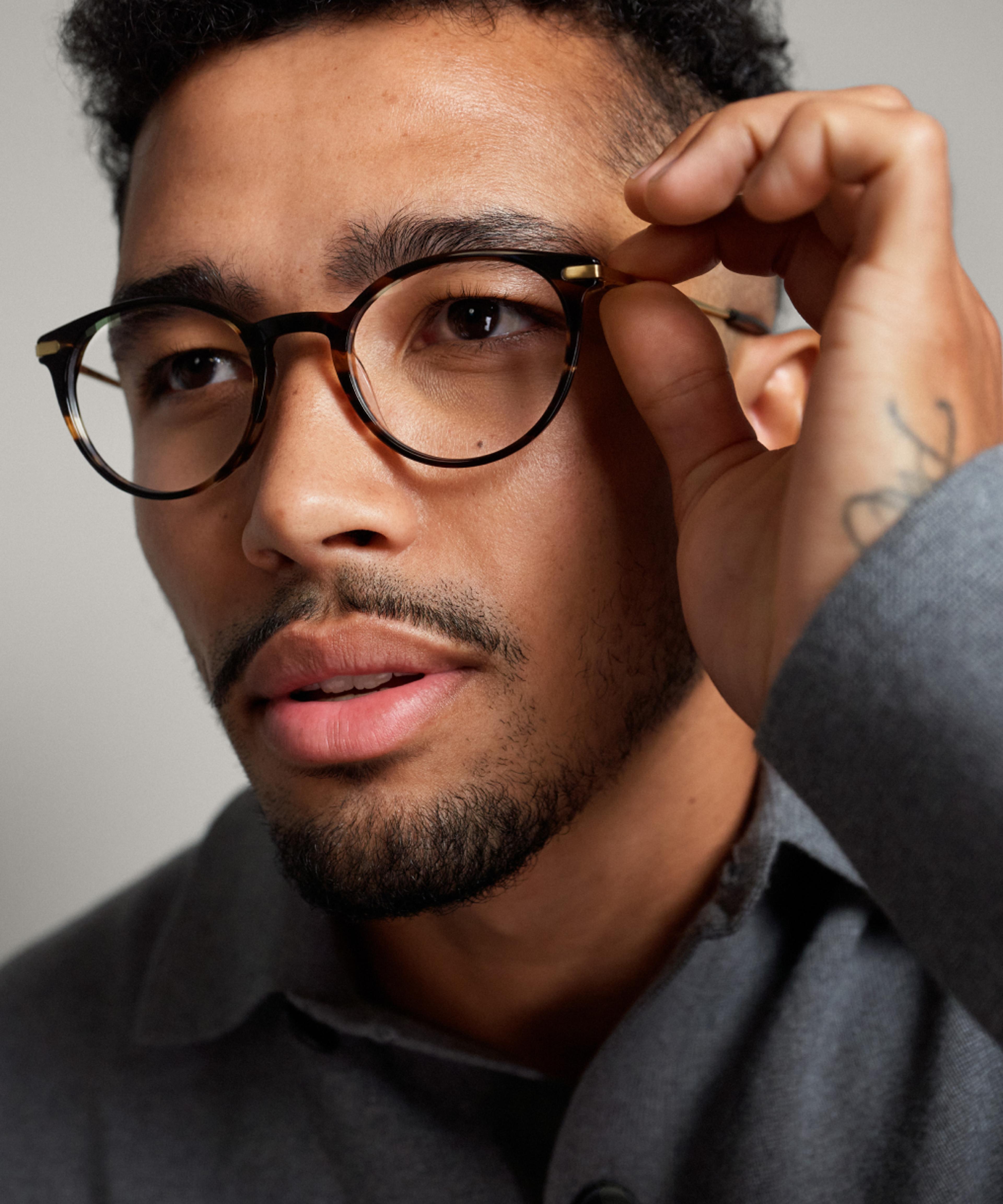 A man is putting on a pair of optical frames.